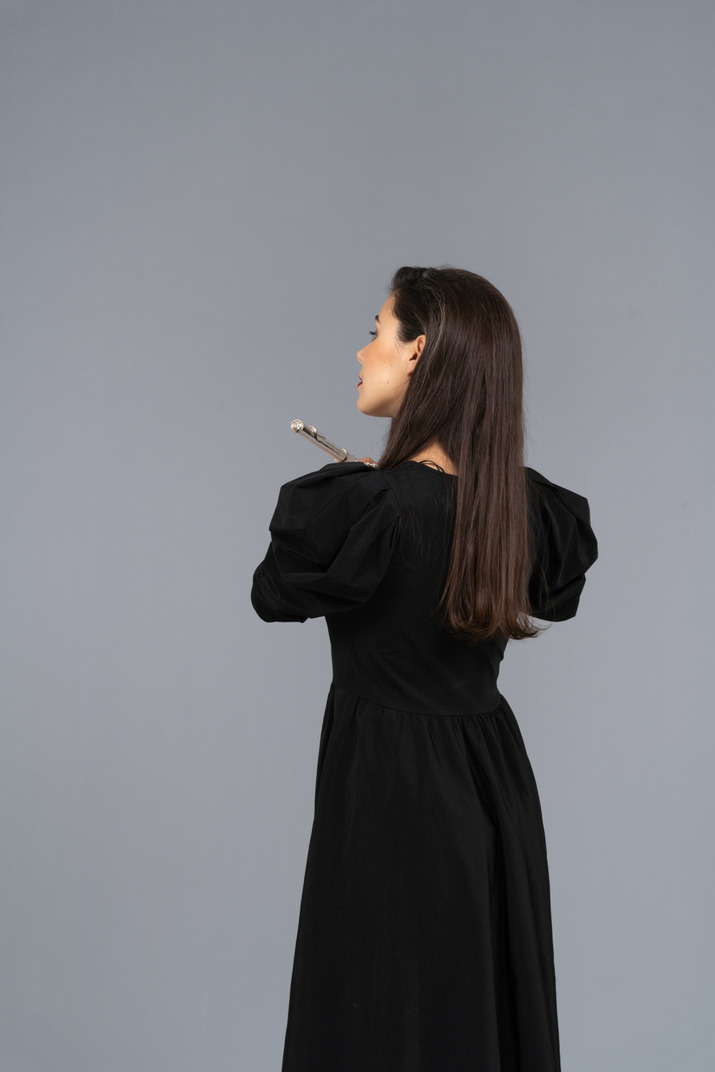Back view of a young lady in black dress holding flute