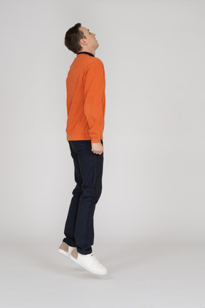 Junger mann im orange sweatshirt springen