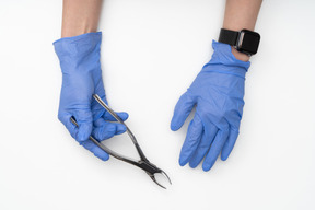 Hands in blue gloves holding a medical tool