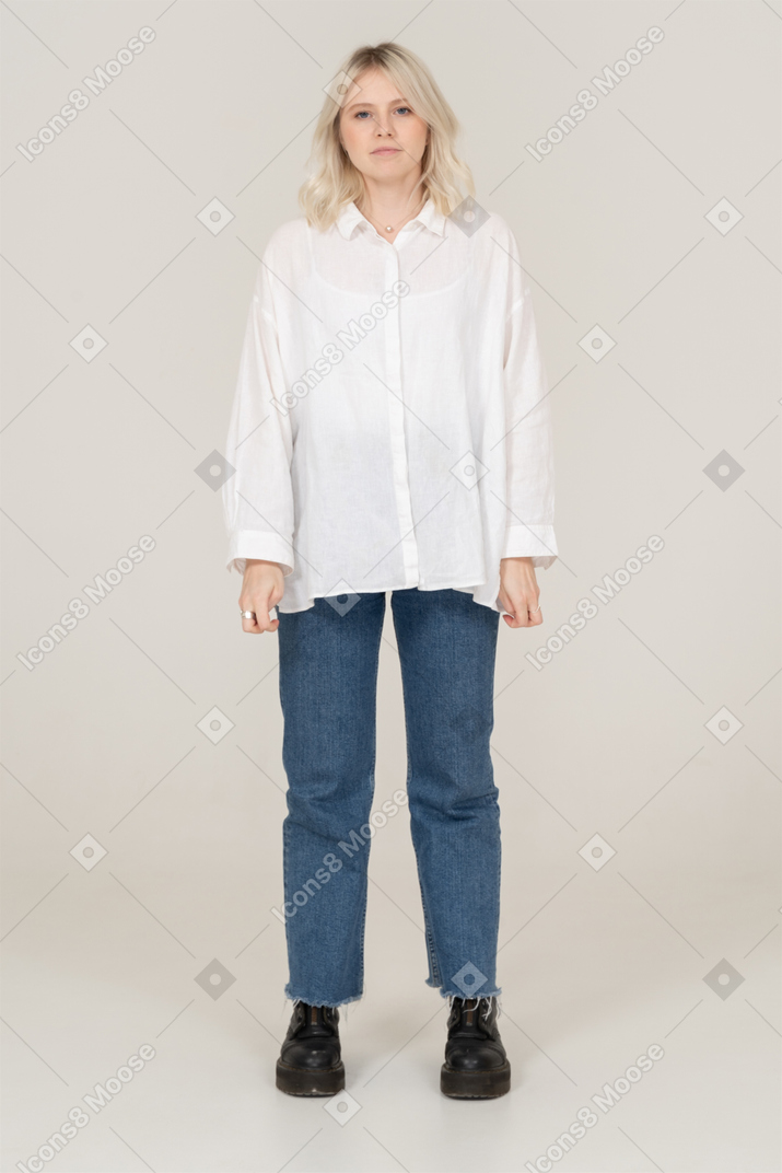 Front view of a blonde female in casual clothes standing still and looking at camera