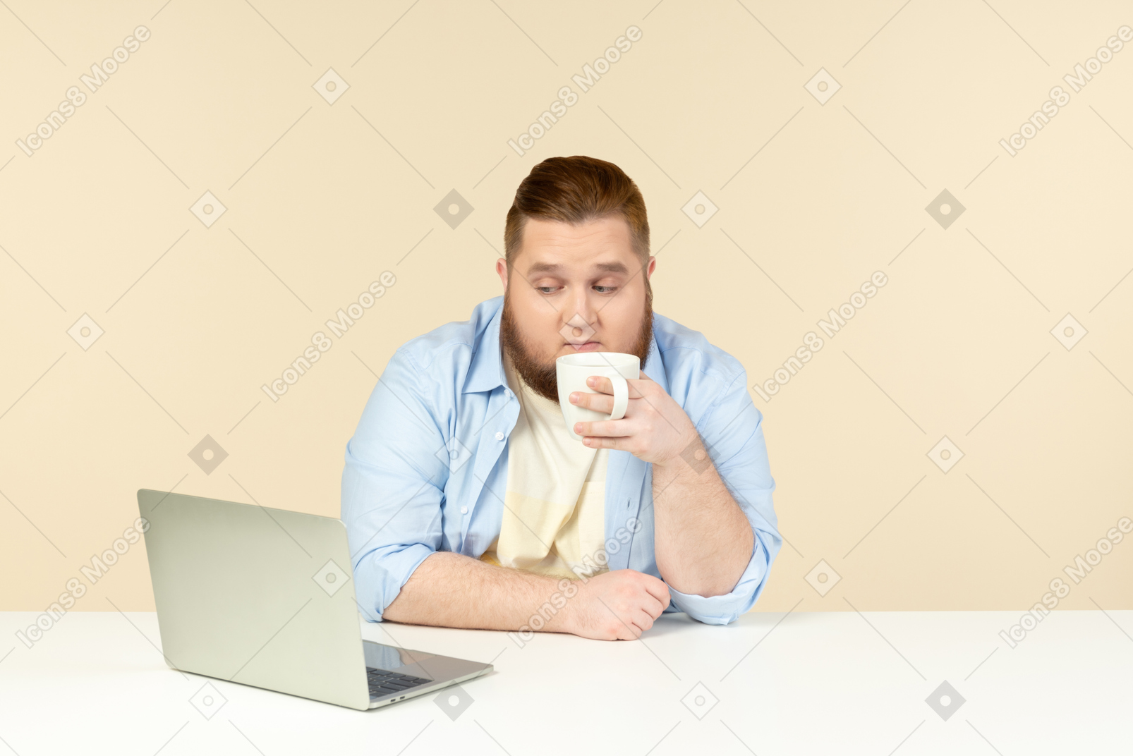 Young overweight man having tea and watching something at laptop