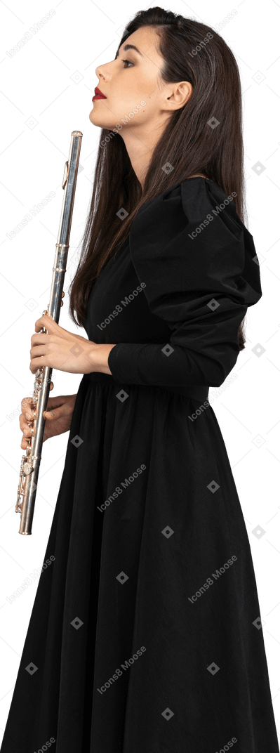 Side view of a serious young lady in black dress holding flute