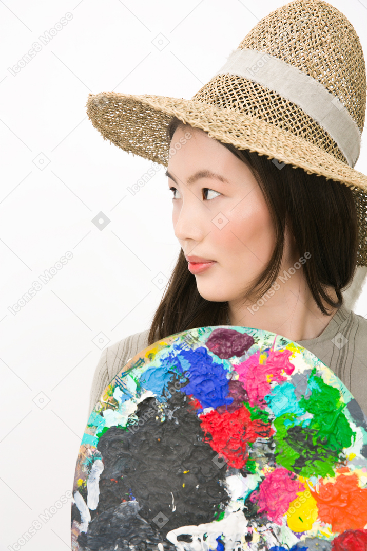 Beautiful young girl looking aside and holding a palette