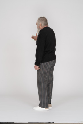 Back view of old man gesturing with hand