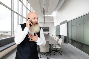 A man with a beard talking on the phone in an office