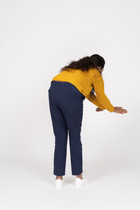 Rear view of a girl in casual clothes bending down with outstretched arms