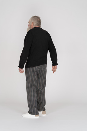 Uomo anziano in piedi con la schiena verso la telecamera