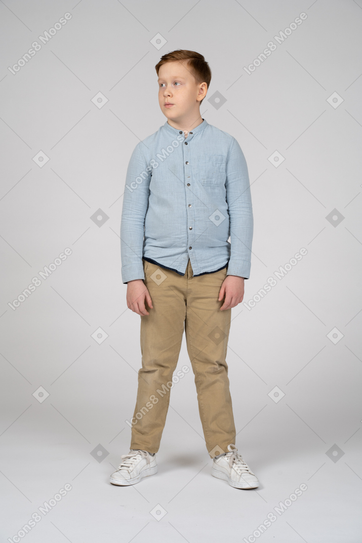 Vista frontal do menino em roupas casuais, olhando de lado