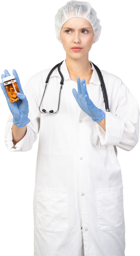 Vue de face d'une jeune femme médecin tenant un pot de pilules