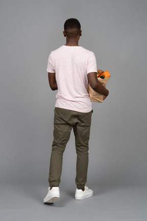 A young man carrying a grocery bag