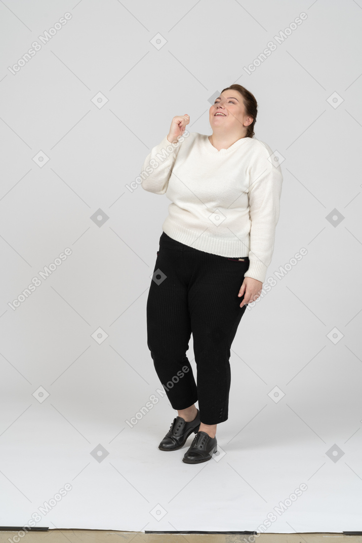 Front view of a happy plus size woman in casual clothes looking up