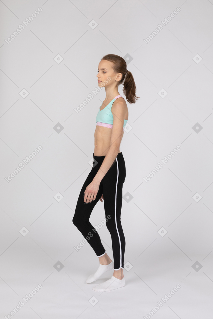 Vista de tres cuartos de una jovencita en ropa deportiva caminando
