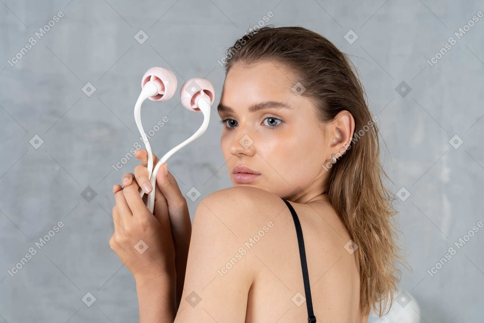 Portrait of an attractive young woman holding face roller