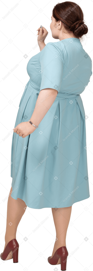 一个穿蓝色裙子的女人走路的后视图