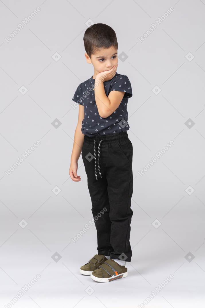 Side view of a thoughtful boy posing with hand on chin