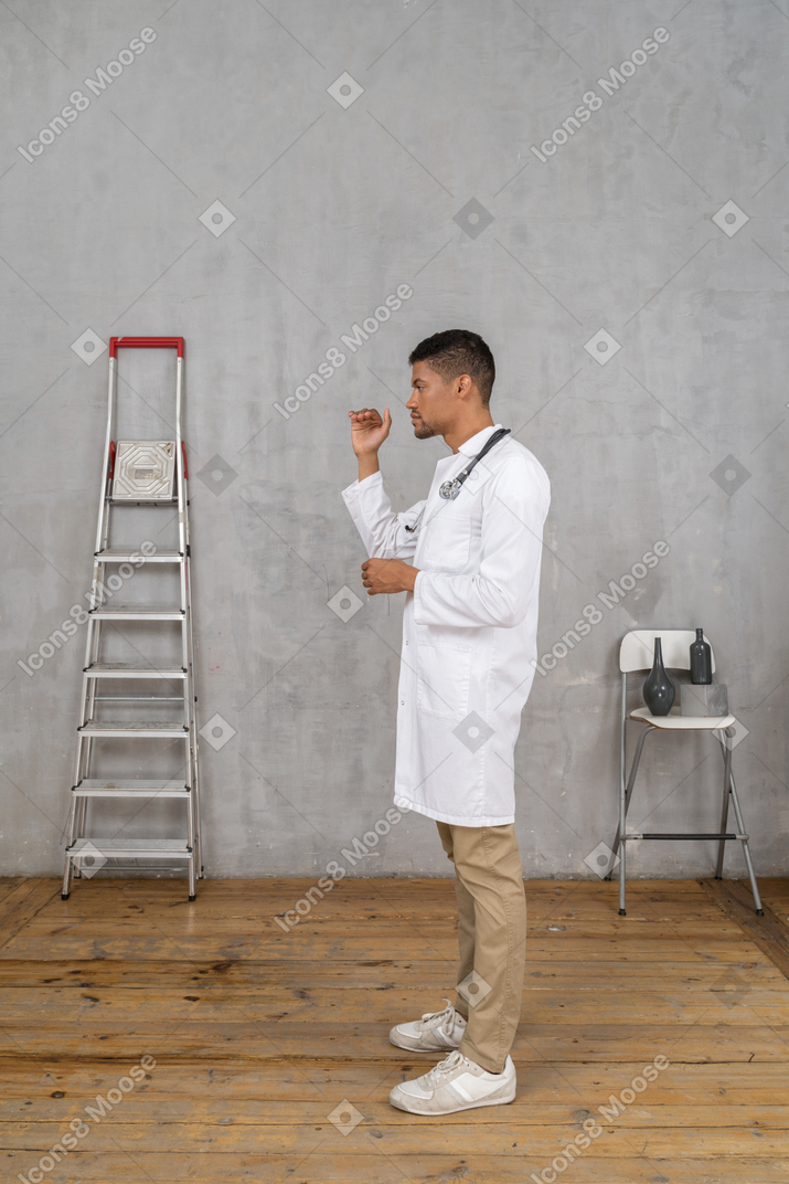一位年轻医生站在一个房间里的侧视图，房间里有梯子和椅子，显示出某物的大小