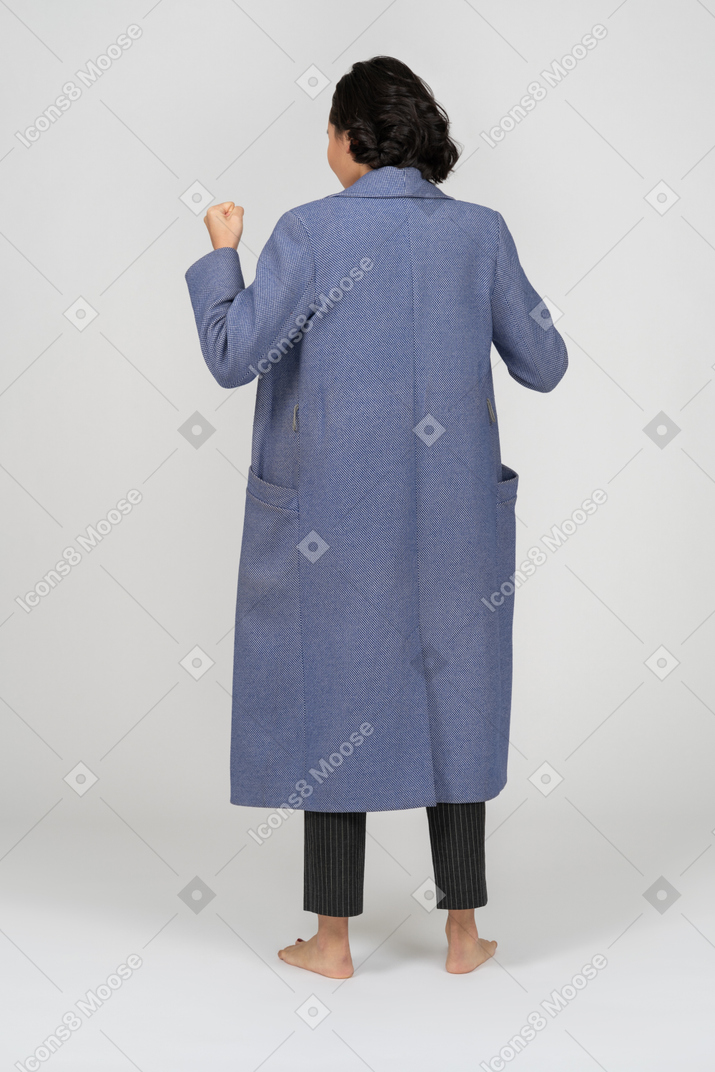 Vue arrière d'une femme en manteau avec le poing levé