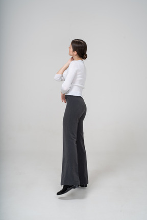 Side view of a woman in black pants and white blouse standing on one leg