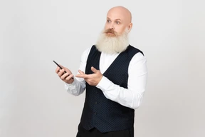 Hombre de edad sosteniendo el teléfono y mirando poco sorprendido