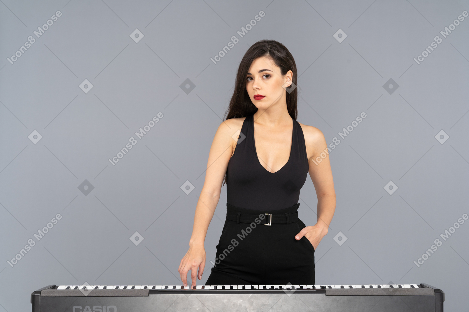 Vista frontal de uma jovem de vestido preto pressionando a tecla de um piano