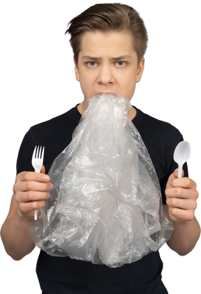 Homem segurando um garfo e uma colher de plástico com filme plástico na boca
