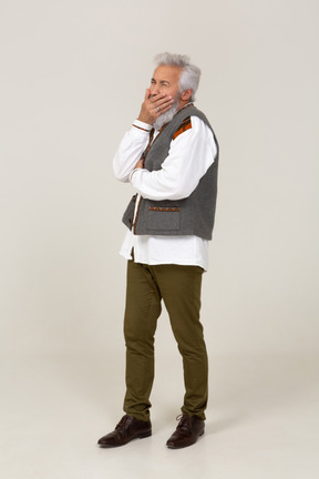 Man in gray vest yawning and covering his mouth