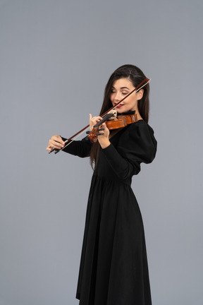 Close-up de uma jovem de vestido preto tocando violino