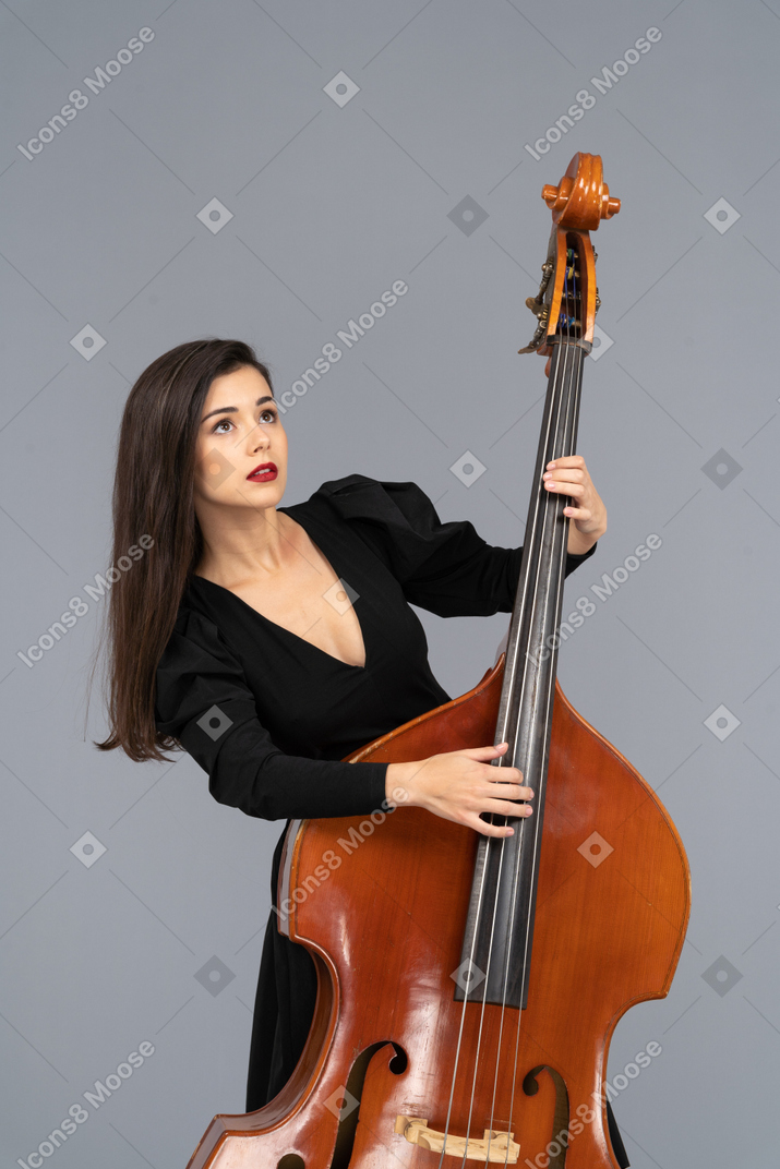 Крупный план молодой женщины в черном платье, играющей на контрабасе