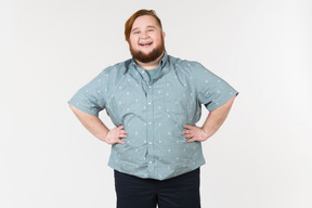 A fat man standing with his hands on his hips and laughing