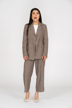 Front view of a grimacing young lady in brown business suit looking aside