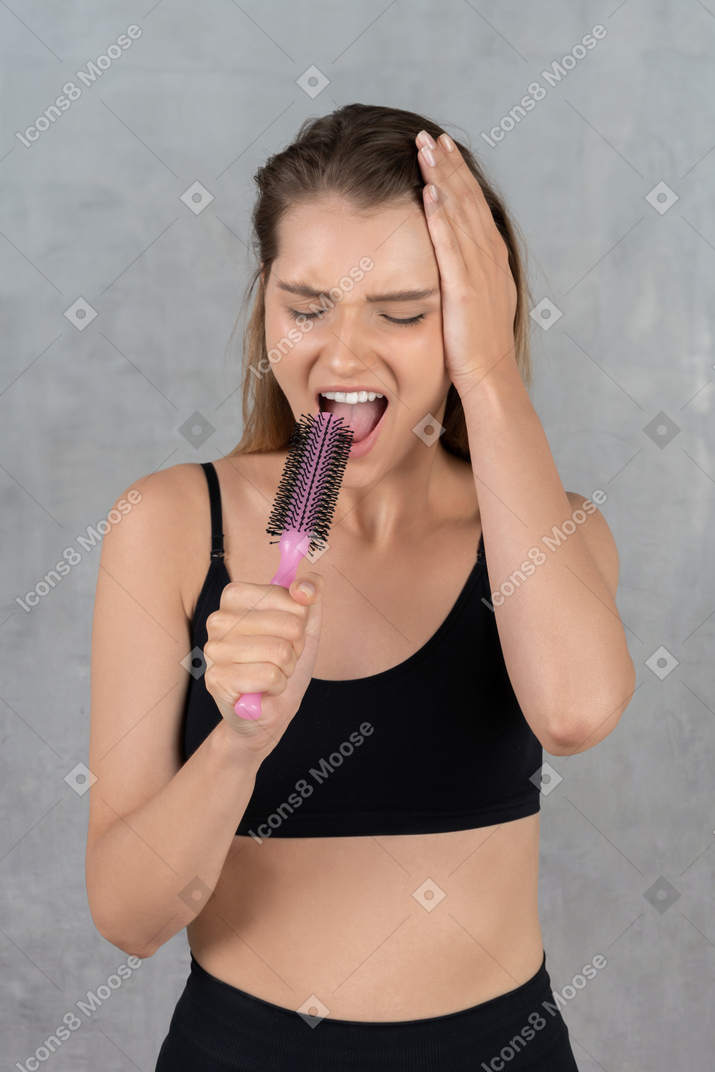 Mujer joven golpeando notas altas con "micrófono" en la mano