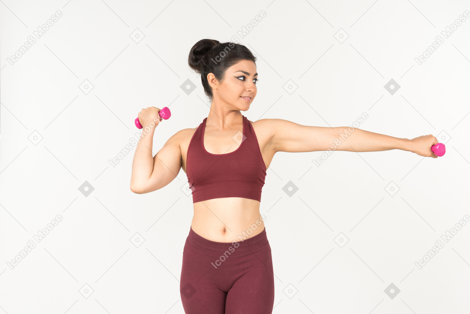 Young indian woman in sportswear holding hand weights and looking aside
