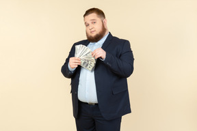 A plus-size man in a black costume with dollar bills in his hands