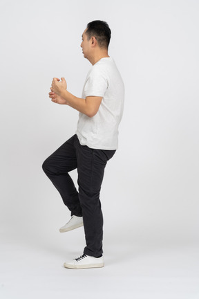 Side view of a confused man standing on one leg