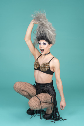 Drag queen squatting and pulling up hair