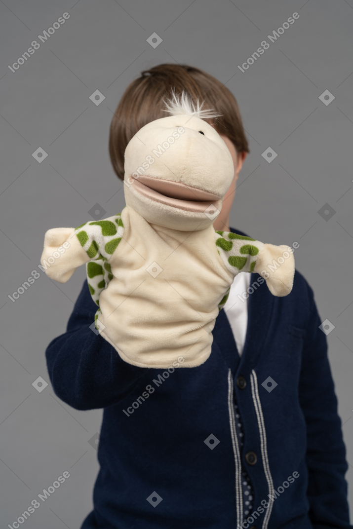 Close-up of a little boy hiding behind a tortoise puppet