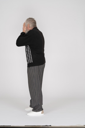 Elderly man covering his face with his hands