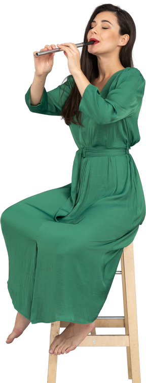 全长的年轻女子，穿着绿色的衣服，坐在椅子上，一边演奏单簧管