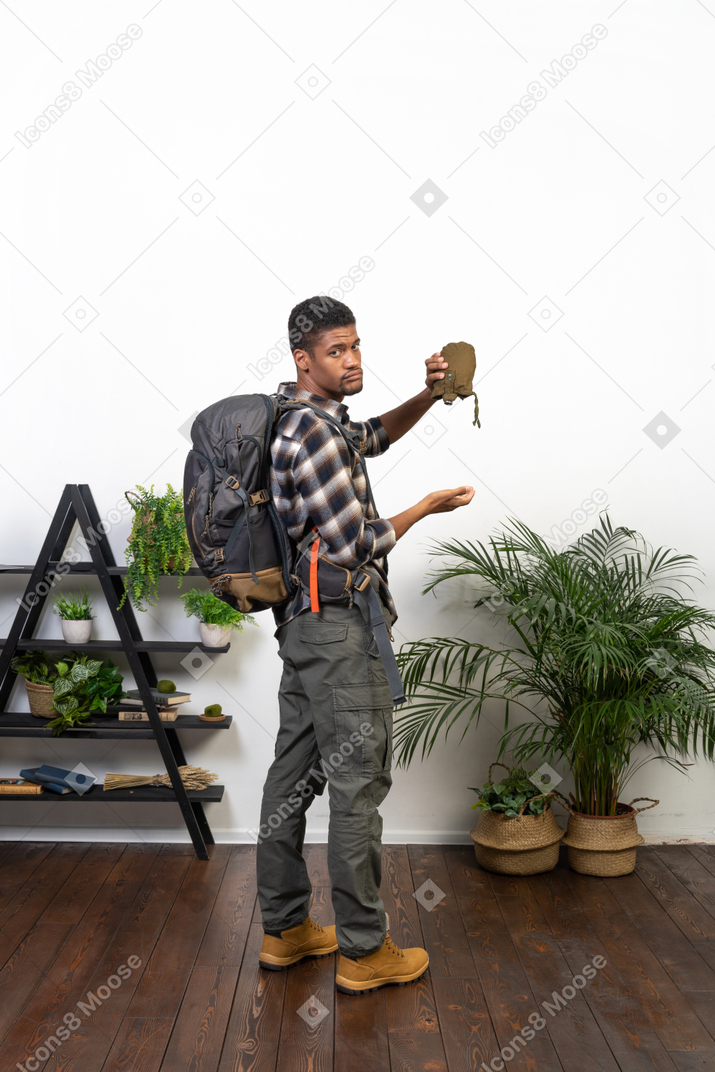 Back view of a thirsty backpacker holding up an empty flask