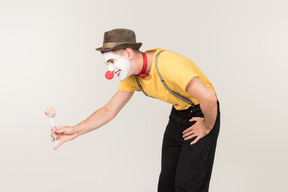 Smiling male clown passing lollipop he's holding