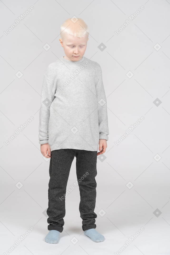 Little boy standing with closed eyes and head down
