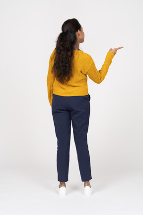 Vista posteriore di una ragazza in abiti casual che indica con un dito