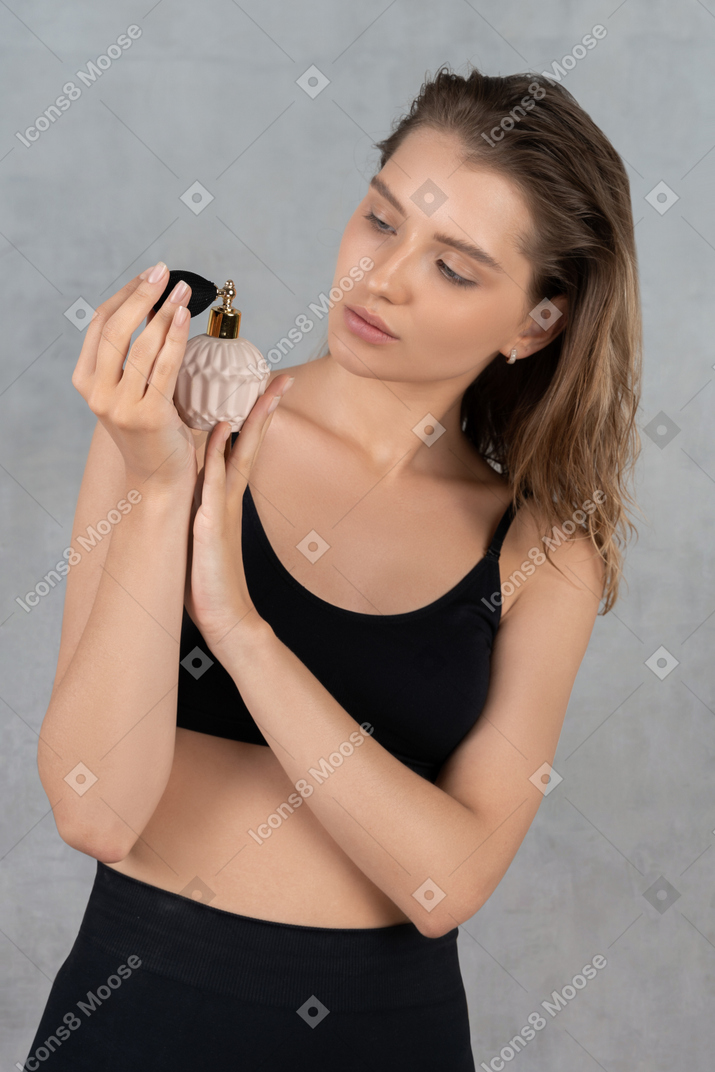 Portrait of a young woman holding bottle of perfume