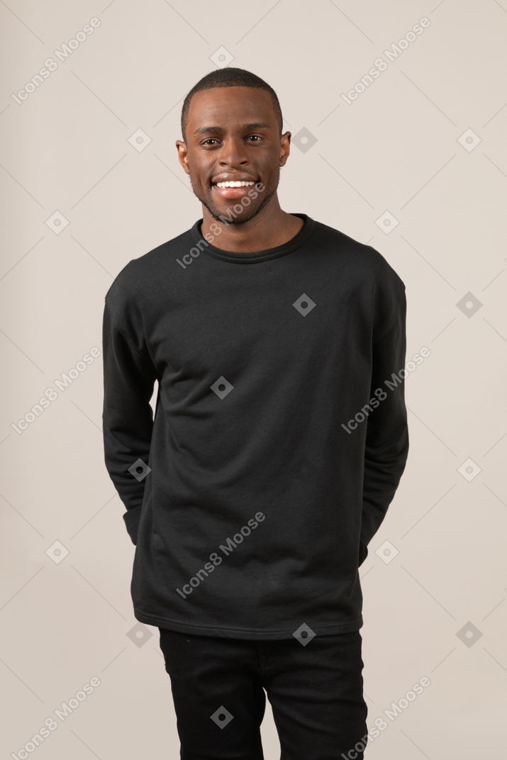 Smiling young man keeping hands in back pockets
