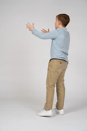A young boy is standing with his arms outstretched