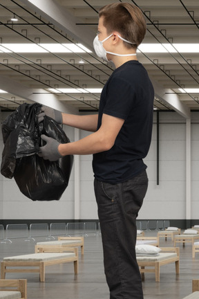 A man wearing a face mask and holding a black bag