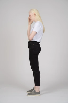 Side view of an upset young woman touching her head