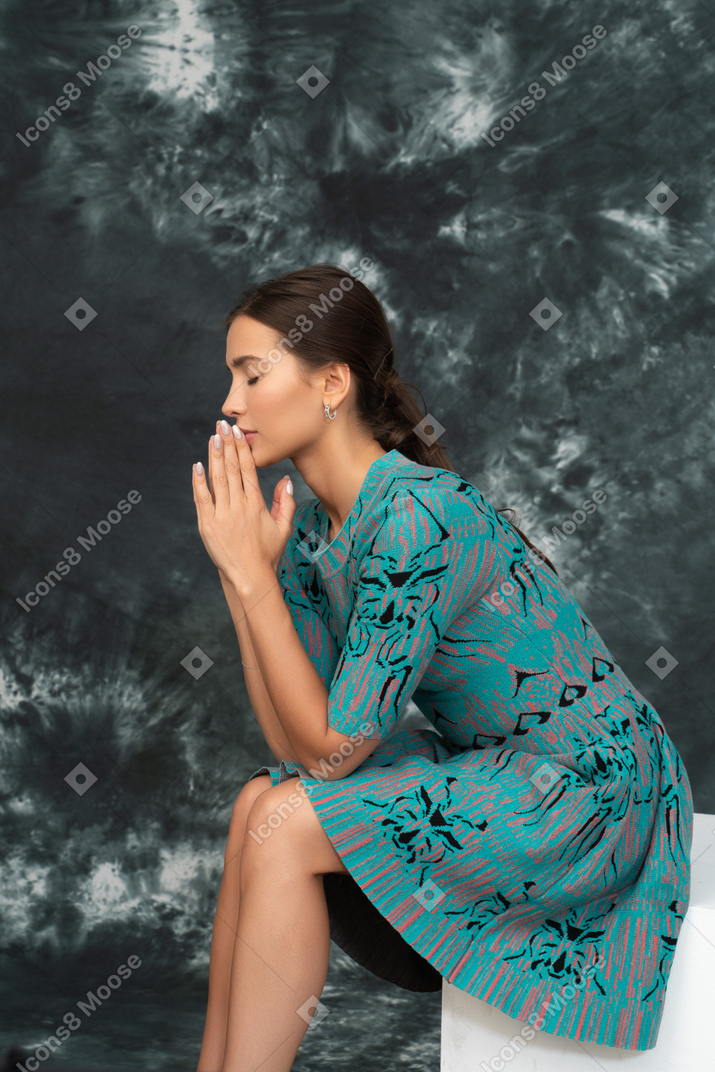 Portrait de côté de jeune femme priant en robe bleue