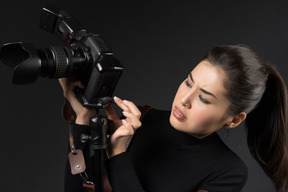 Beautiful female photographer adjusting a camera