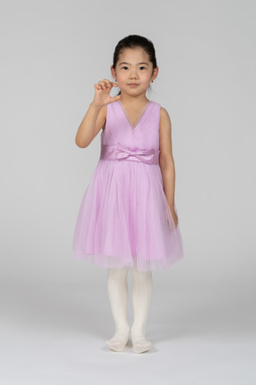 Little girl in pink dress showing size of something small